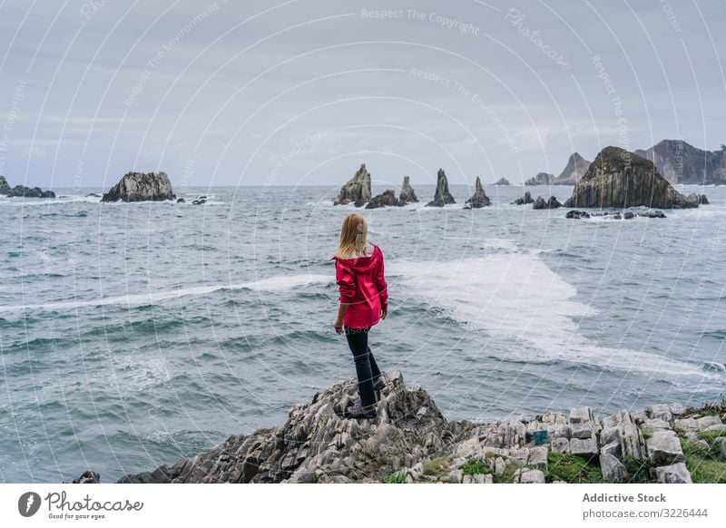 Woman on stony seashore looking on foamy water washing peaks woman watching vacation tourism holiday relaxing adventure traditional destination ocean coastline