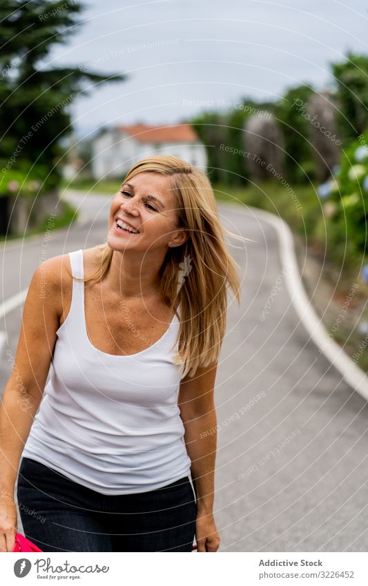 Joyful woman walking on marked road looking away street travel urban vacation lady park active path trip fashion green modern journey adventure human model