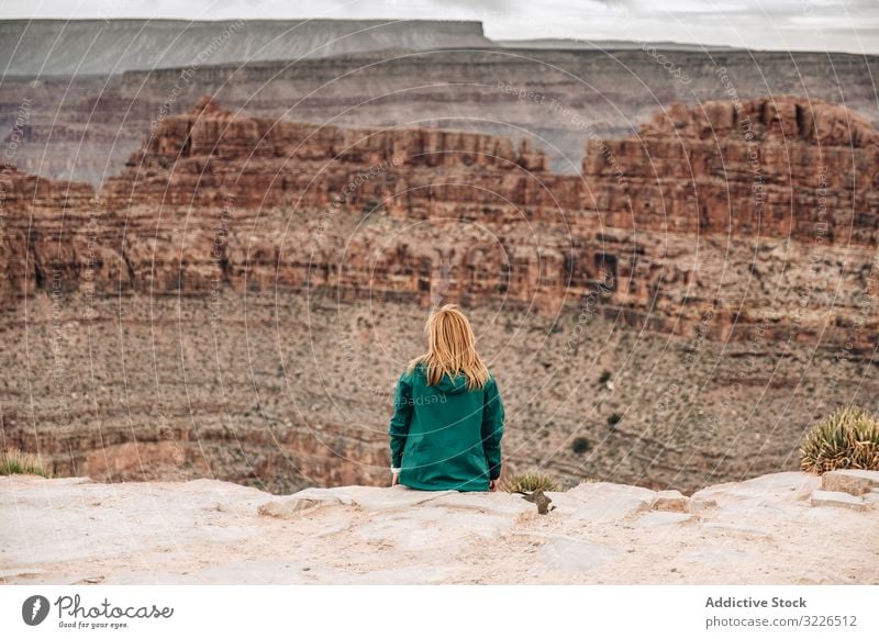 Female relaxing on cliff and admiring picturesque view woman canyon rest rock admire female tranquil jacket usa nature lifestyle hiking active sportswear sit