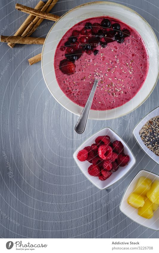 Smoothie bowl with fresh berries and sesame served on table smoothie mango cut cinnamon kitchen cloth rustic super food plate spoon wooden colorful raspberry