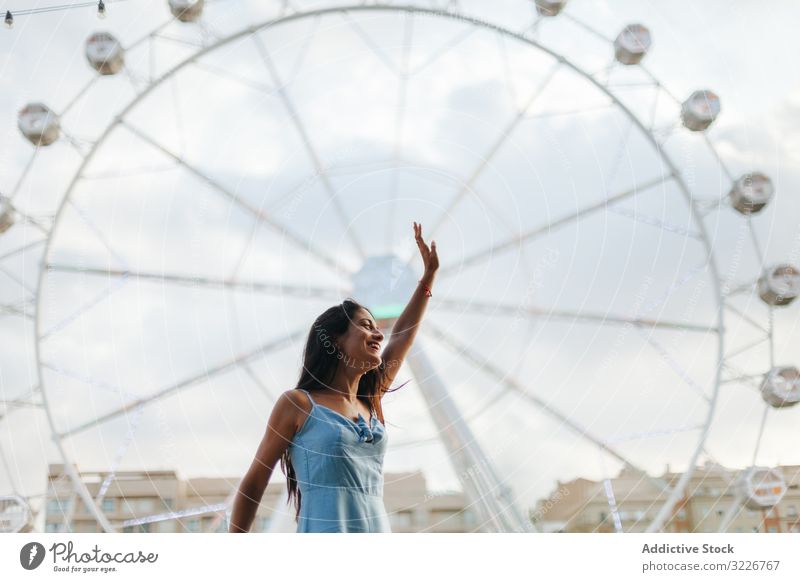 Dreamy woman resting by Ferris wheel in amusement park dreamy summer fairground sundress ferris wheel relaxed calm entertainment wistful long hair attractive