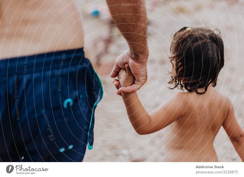 Grandfather and granddaughter walking on beach holding hands handshake grandfather vacation family tender embracing elderly child girl granddad enjoying bonding