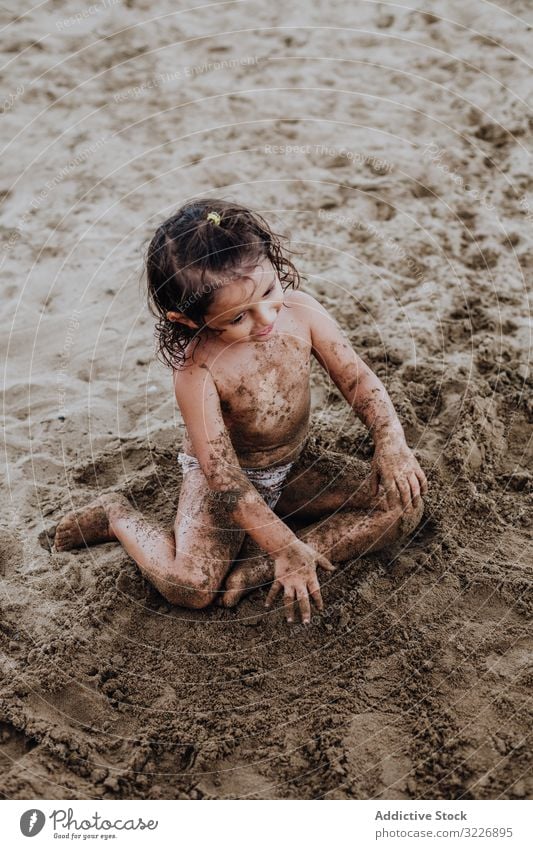 Inspired child playing with sand on beach summer vacation smeared digging holiday fun mouth girl game enjoyment expression activity cheerful joyful small