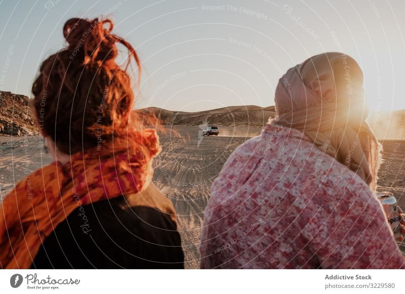 Anonymous travelers looking at car in desert sand arid together morocco africa sunny daytime journey adventure tourism landscape dry terrain vacation nature