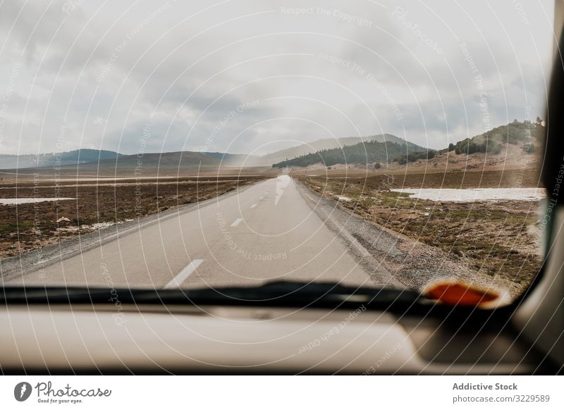 Road trip on cloudy day road vehicle sky hill plain morocco africa weather nobody car window vacation journey travel tourism auto transport windshield