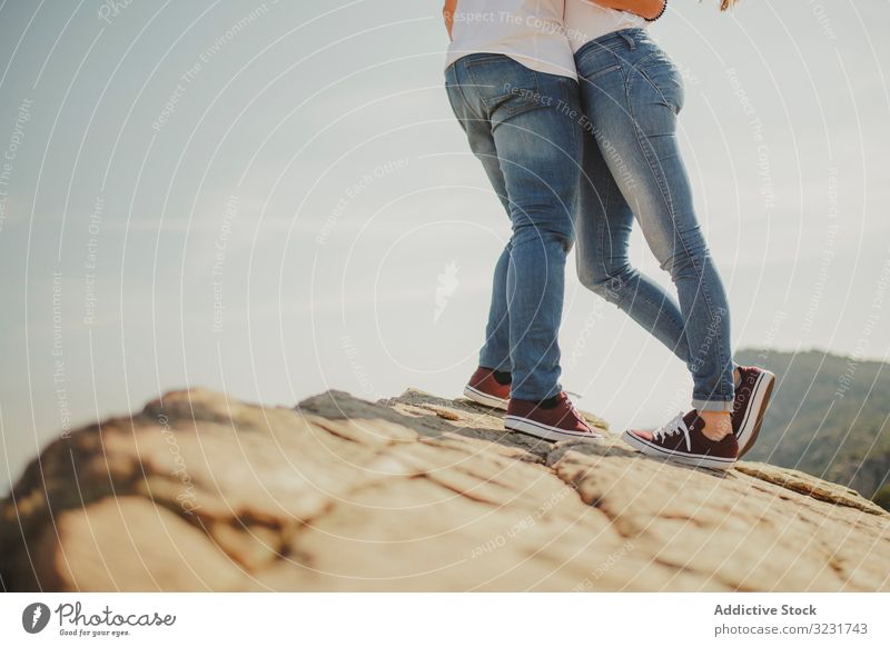 Loving couple embracing while standing at mountain cliff embrace love travel romantic hugging summer hilly slope cheerful modern casual matching identical young