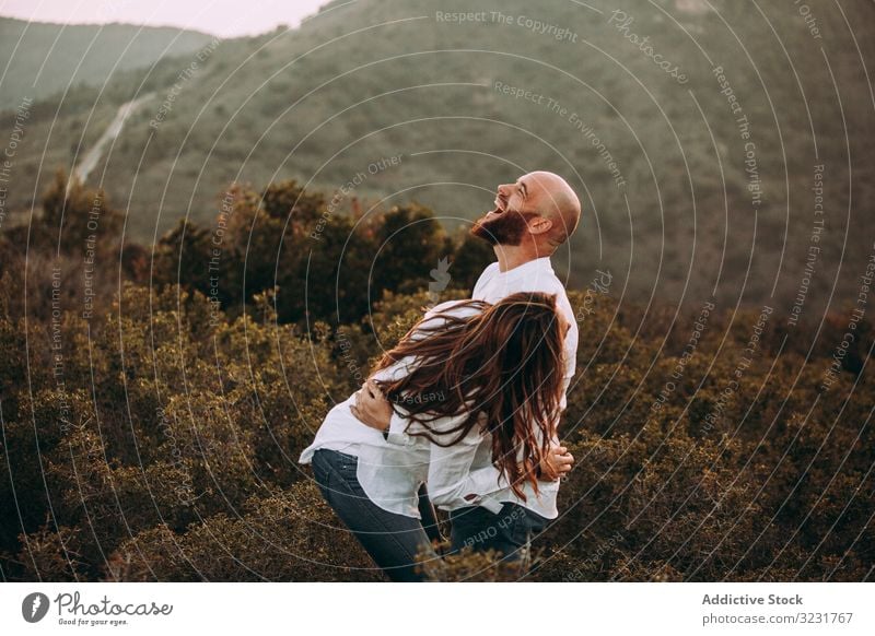 Affectionate couple having fun on hilly valley affectionate field nature happy mountain love smile hills countryside white shirt grass young adult together