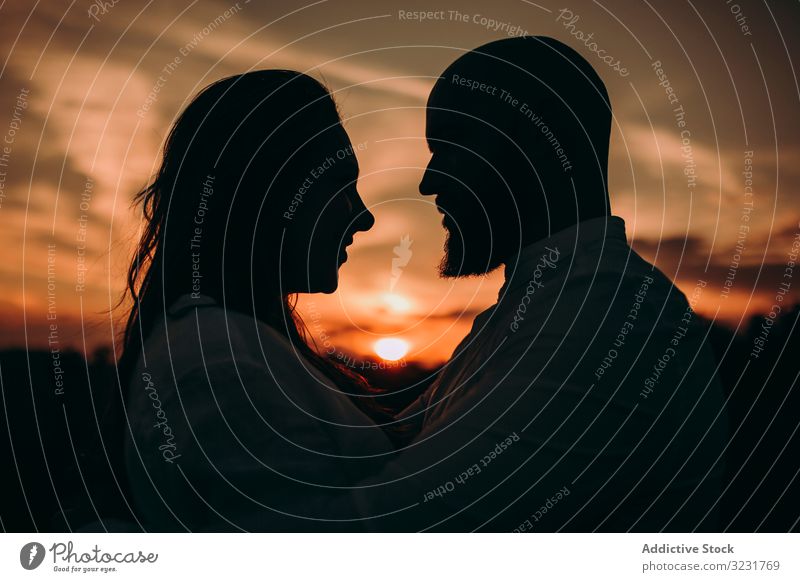 Loving couple embracing while standing against sunset sky silhouette close love tender field countryside twilight valentine together beautiful summer freedom