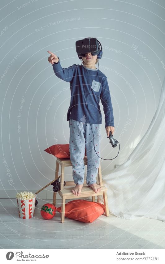 Happy child in VR headset vr play goggles win joystick goal sport popcorn leisure fun arms raised pretend game happy weekend simulator interaction enjoy device