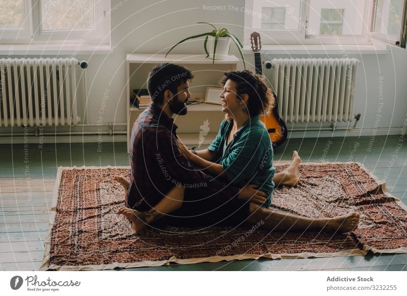 Loving couple embracing while sitting on apartment floor embrace loving cuddling tender casual smile carpet home love together happy hug romantic relationship