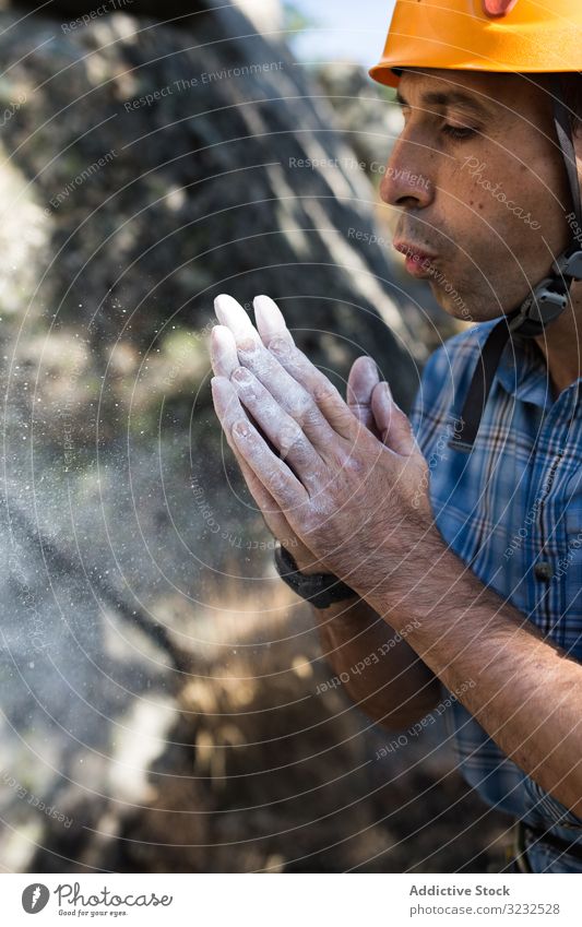 Climber blows chalk powder from his hands sport mountaineering man adrenaline difficult strength strong athletic person climb adventure nature training outdoor