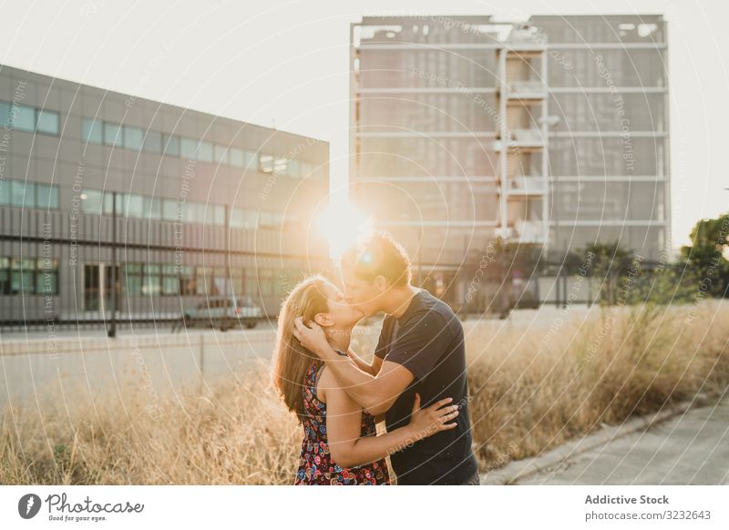 Romantic couple kissing in sunlight in city street urban bonding love romantic happy relationship affection together sensual casual fashion date summer holiday