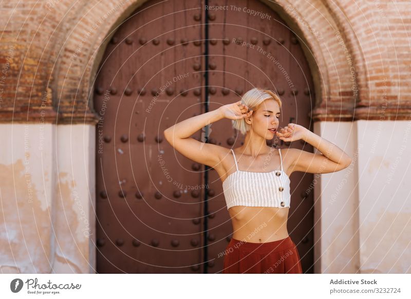 Young lady near old gate woman street ancient building folded arms closed eyes slim young tourism female travel trip aged exterior town city weathered grungy