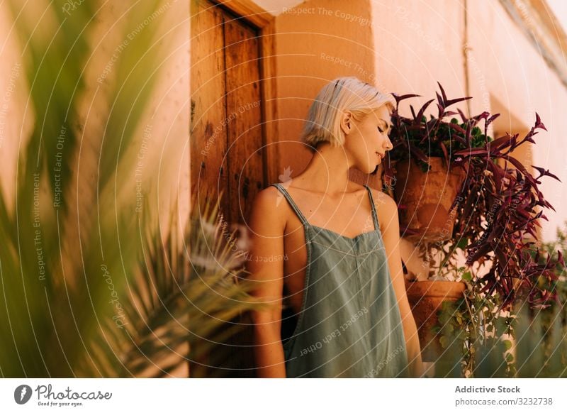 Sensual woman leaning on door wall town street closed eyes sunny daytime sensual young female rest relax lifestyle alley building exterior structure