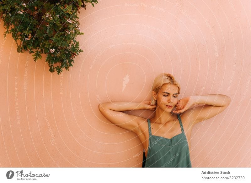 Sensual woman leaning on wall town street closed eyes sunny daytime sensual young female rest relax lifestyle alley building exterior structure construction