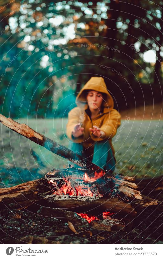 Traveling woman warming hands near campfire on forest glade tranquil flame contemplate relax solitude calm quiet silence firewood freedom enjoy serenity