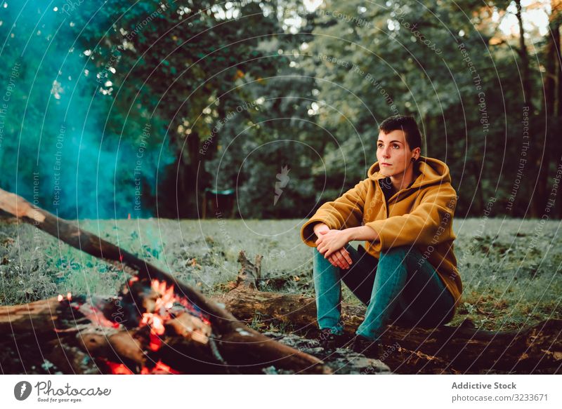 Traveling woman warming hands near campfire on forest glade tranquil flame contemplate relax solitude calm quiet silence firewood freedom enjoy serenity