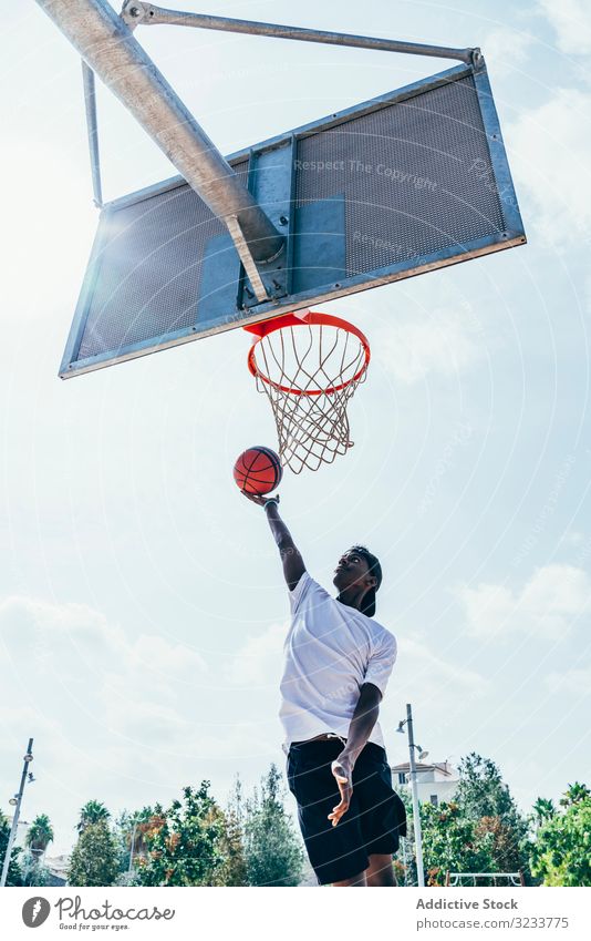 African American sportsman hanging on basketball lap kicking net slam dunk game player stadium playing sportswear activity field male powerful fit athlete