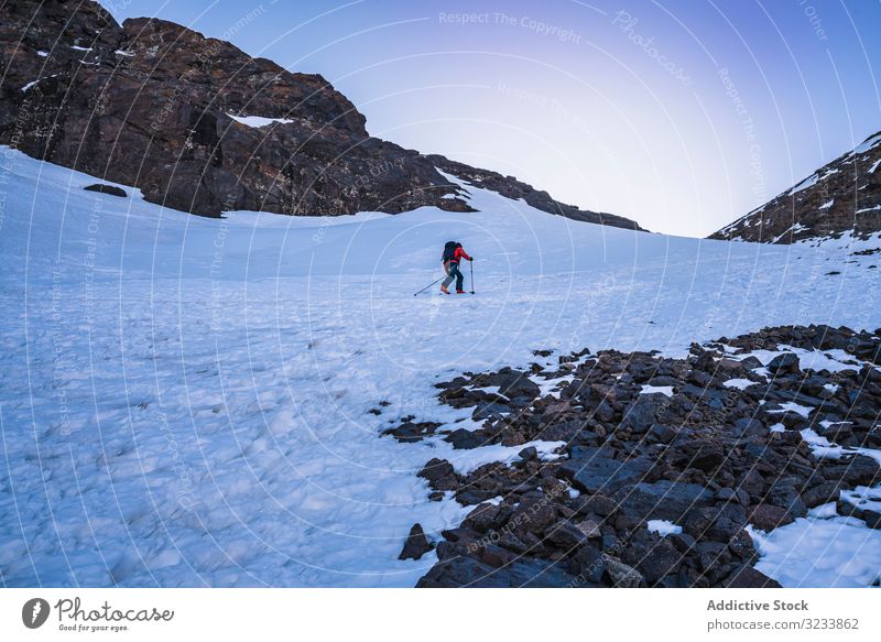 Tourist gazing at breathtaking snowy mountain slope tourist hiking backpack equipment contemplating africa morocco toubkal stand rocky colorful jacket person