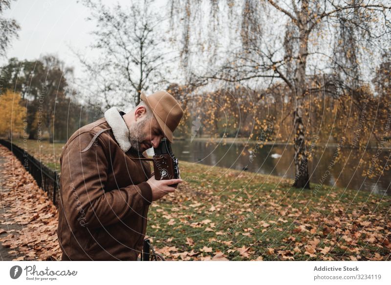 Male photographer standing in autumn park man photo camera retro london casual peaceful adult male great britain england vintage leaf fall season tree shoot