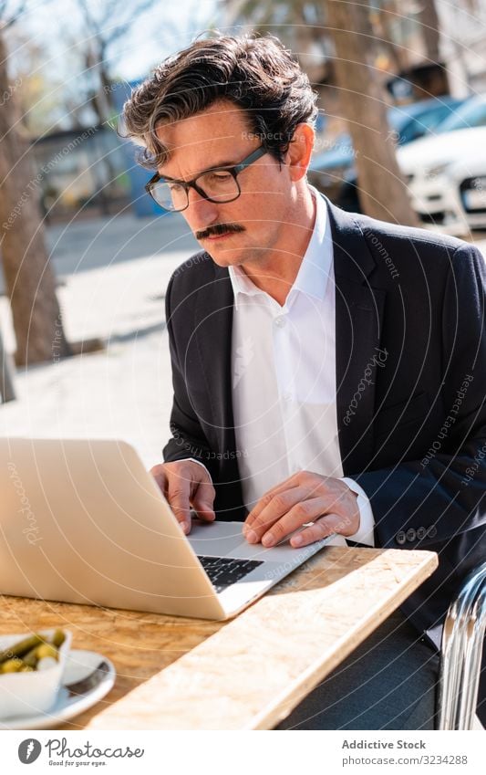 Elderly man using gadget while relaxing at cafe tablet digital smart browsing watching male elderly aged senior device working connection lifestyle professional