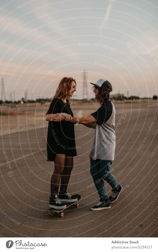 Teenage boy helping girlfriend to skate on road teenage skateboard learn couple together fun practice happy support cheerful urban cool modern generation ride