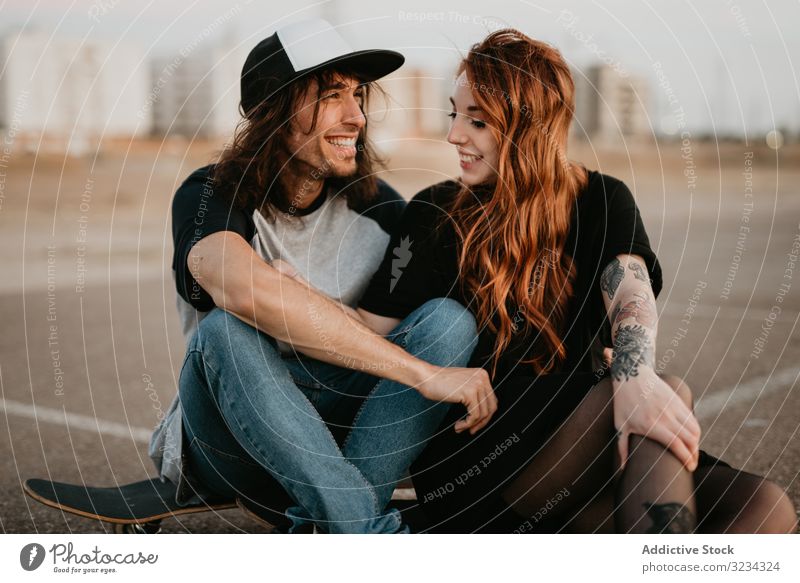 Skaters sitting on empty rural road chatting in sunlight couple teen skater together generation sport countryside hipster asphalt in love fun active modern