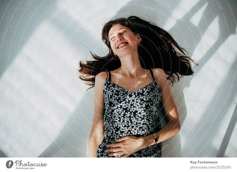 carefree brunette woman lying on the floor laughing Happiness Woman amusement attractive beautiful beauty brown brown hair casual caucasian cheerful coolness