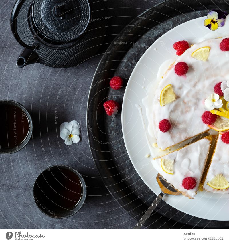 Tea with cake - light glazed cake with raspberries, lemons and pansies served with black tea ware Cake Candy lemon cake Raspberry Lemon Icing To have a coffee