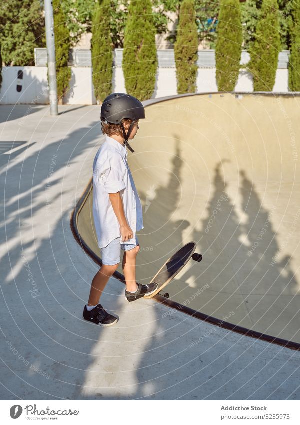 Child in helmet riding skateboard child skatepark ramp ride sunlight sport leisure hobby boy young wear childhood summer sunny active fun style urban lifestyle