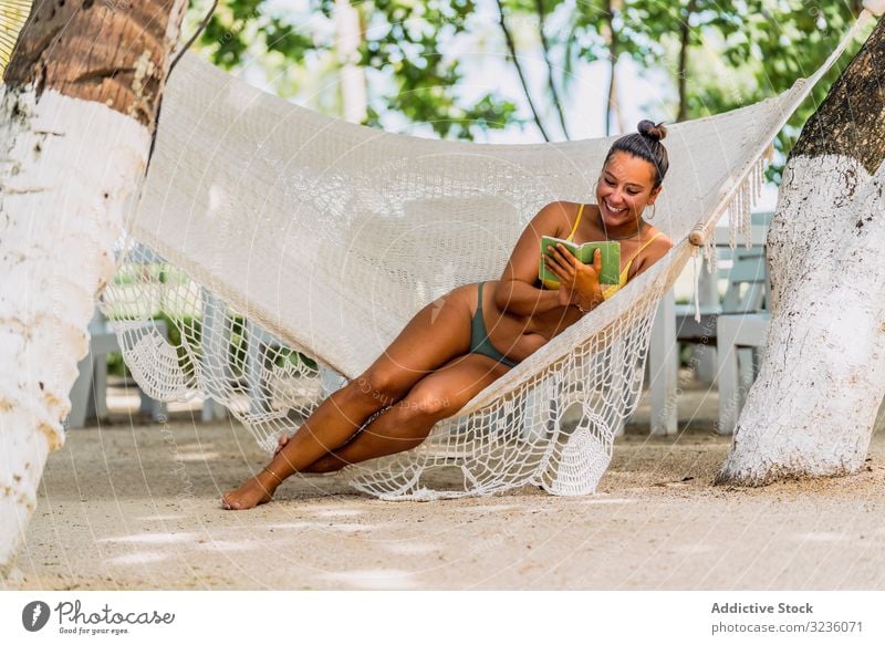 Joyful woman in bikini resting in hummock on beach sit joyful happy smile exotic seaside tanned barefoot relaxed young adult fit vacation costa rica shore