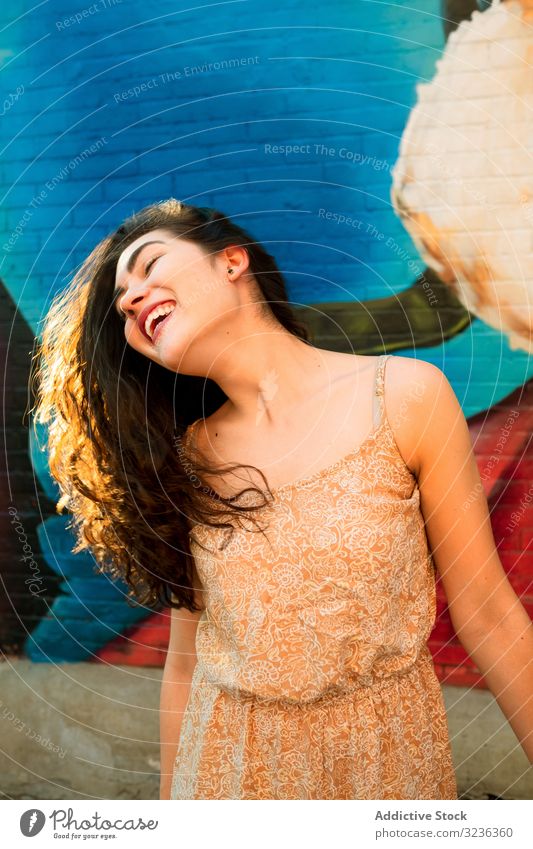 Funny woman making silly face on street funny having fun tilt stand opened mouth urban brick wall graffiti smile joke colourful bright youth summer young adult