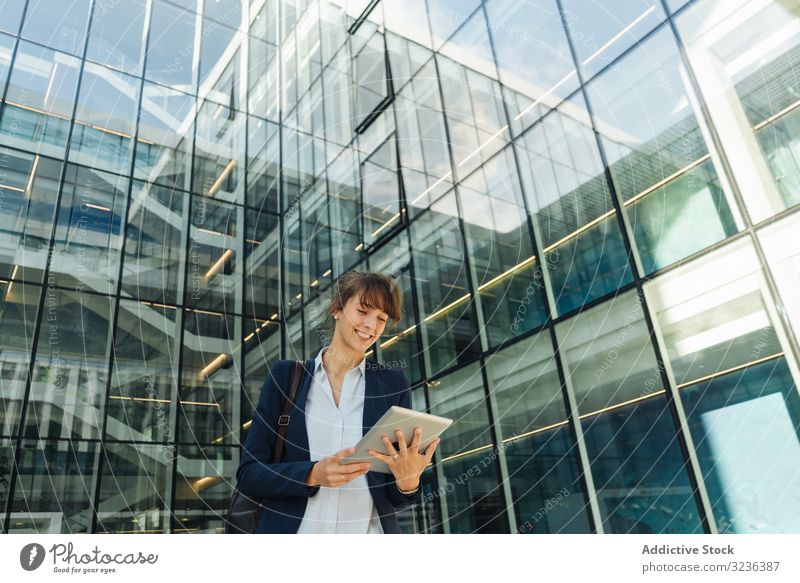 Positive businesswoman using tablet on street city positive modern smile adult building female elegant casual confident urban town contemporary work glass wall