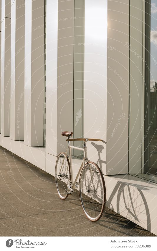 Bicycle parked outside modern building bicycle street city sidewalk urban transport exterior contemporary downtown commute structure construction pavement path