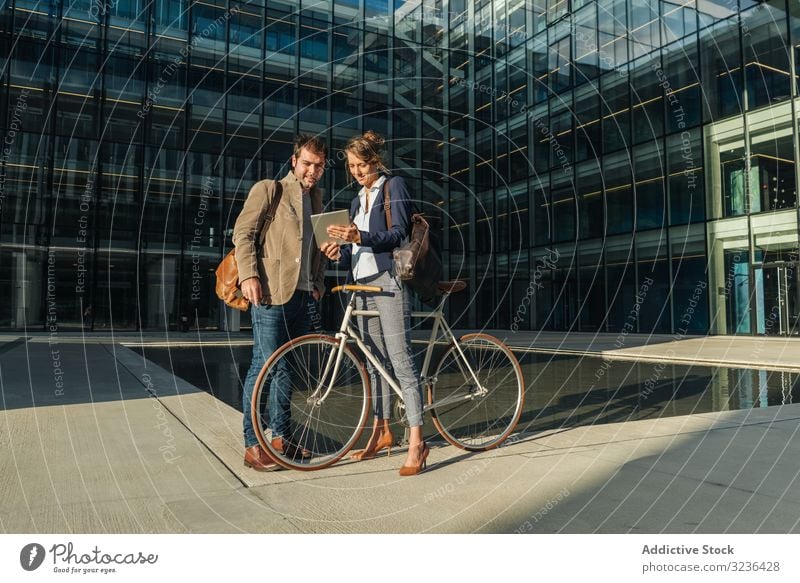 Businesspeople talking on street after work businesspeople smile building bicycle man woman colleague together couple office casual city town urban modern