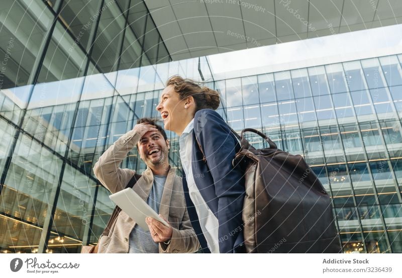 Cheerful colleagues using tablet after work businesspeople street smile social media building man woman together couple office casual city town urban modern