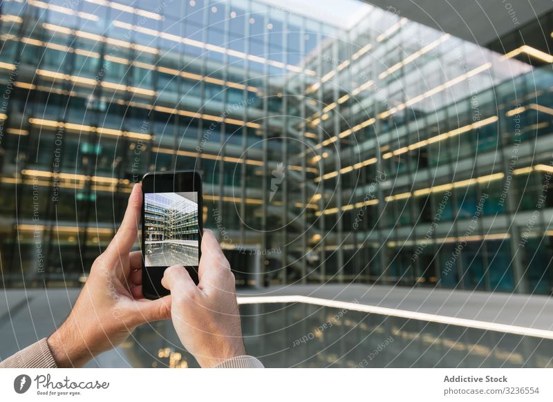 Man shooting building facade with smartphone in downtown taking photo skyscraper man business screen street urban photography transparent share architecture