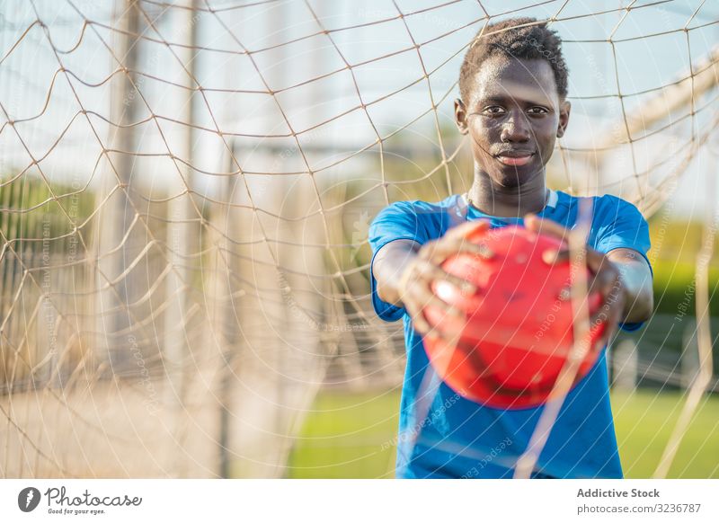 African American football player with ball teenager outstretched arms sky cloudless training sportswear ethnic show male adolescent soccer lawn black