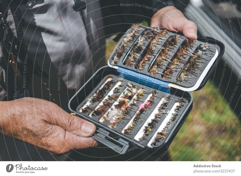 Fisherman demonstrating collection of baiting in box fisherman demonstrate show arranged lure stand rural meadow hook aged senior casual row skill equipment