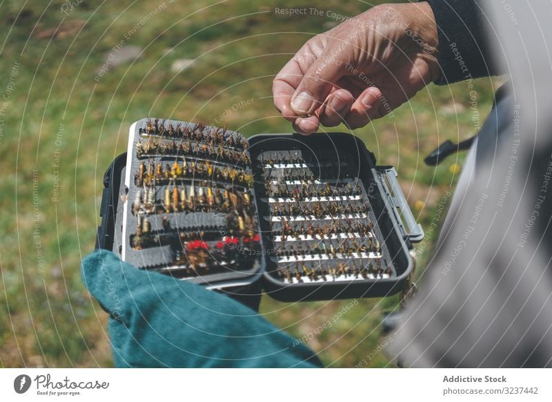 Fisherman demonstrating collection of baiting in box fisherman demonstrate show arranged lure stand rural meadow hook aged senior casual row skill equipment