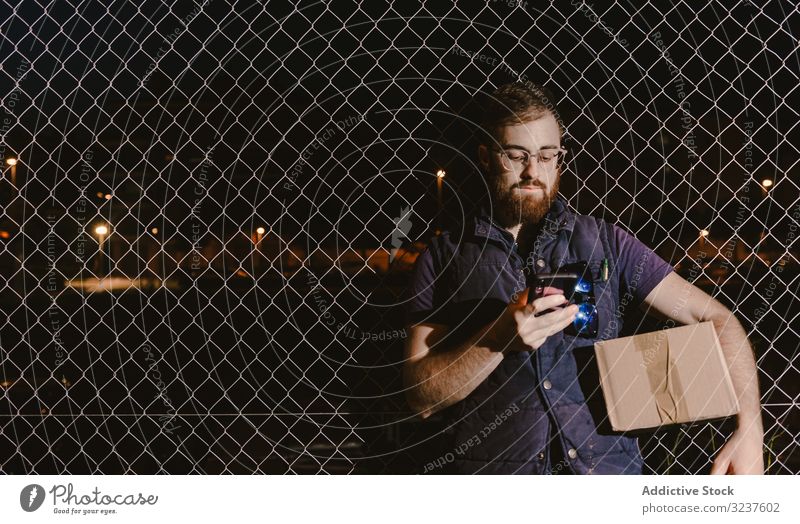 Courier with carton waiting client on street in evening man box courier delivery shipment service destination distribution order express package male