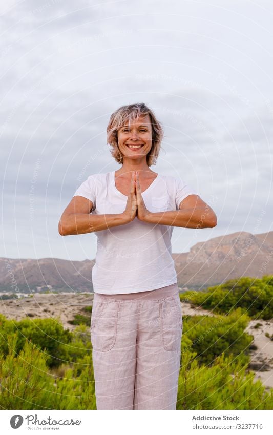 Barefoot woman meditating on stone meditation exercise rock tai chi clasped hands nature sky cloudy training female adult barefoot breath healthy fit yoga