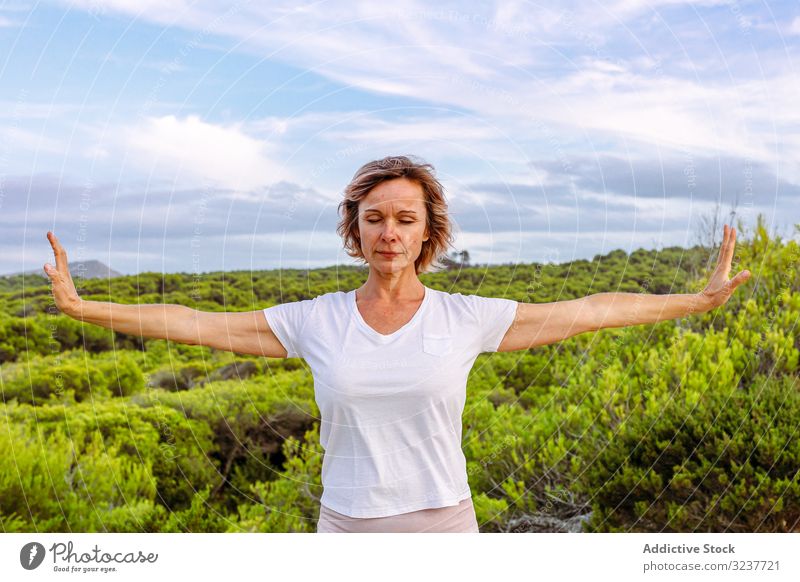 Adult woman practicing martial arts in nature gesture exercise tai chi closed eyes meditation sky cloudy training female adult breath healthy fit yoga