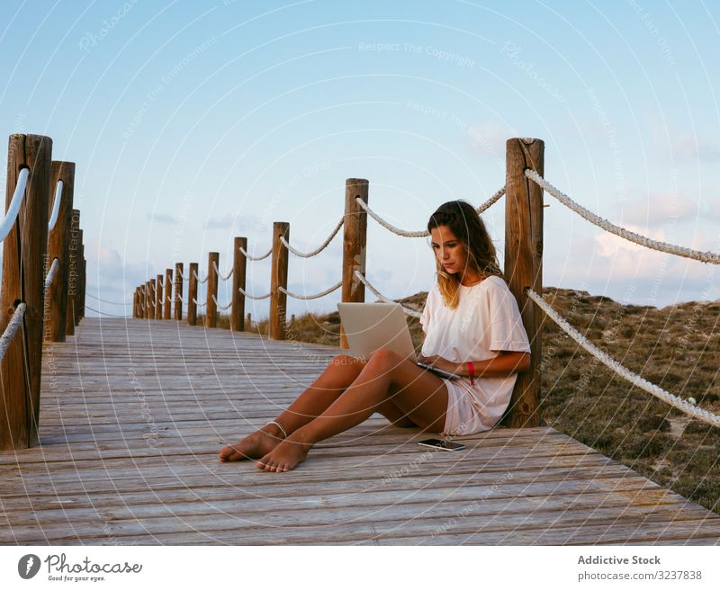 Smart resting woman remote worker using laptop while lying on bridge freelancer browsing computer young female working nature devises gadgets vacation travel