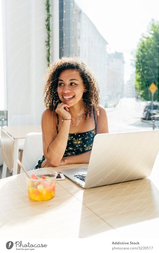 Woman using laptop in cafe woman drink healthy juice ethnic table window female sit lifestyle rest relax glass smoothie detox beverage lady curly hair