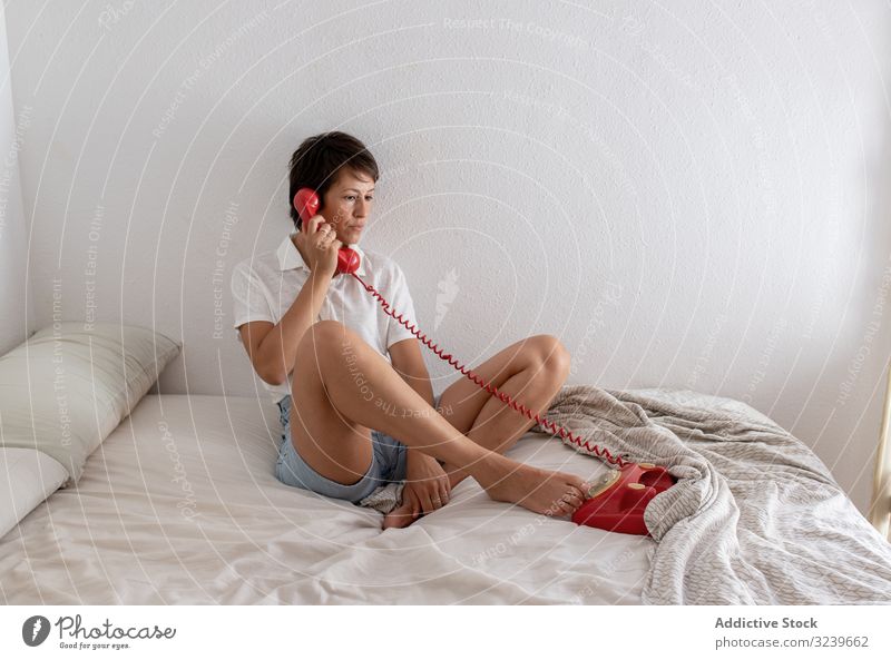 Pensive woman having telephone conversation upset bed listen dialogue call bedroom wall female sit home apartment flat retro vintage communication speak talk