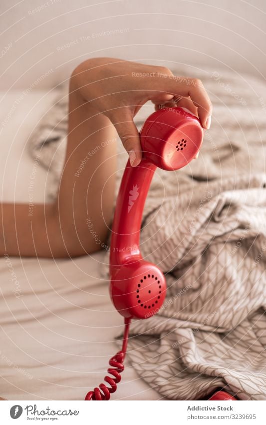 Crop woman hanging up telephone hang up handset end conversation bed rest lying home female comfort cozy retro vintage red apartment flat blanket relax lady