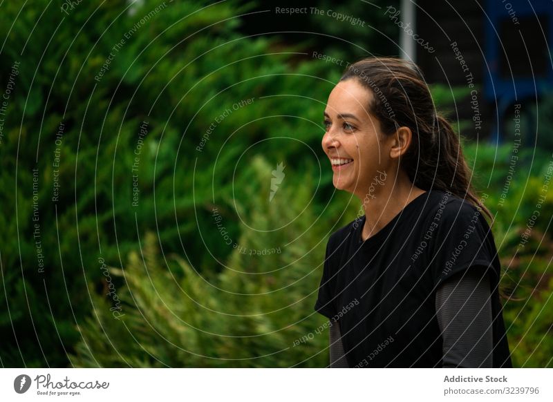 Cheerful woman resting in garden during training smile break sportswear bush green female fitness healthy taiji retreat wellness wellbeing summer nature