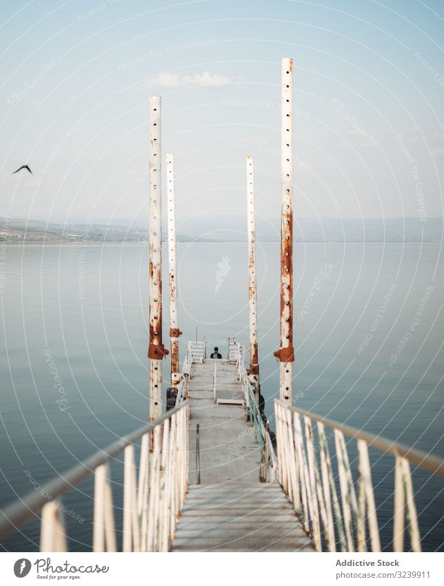 Rusty pier near calm sea water rusty narrow railing sky cloudless weathered traveler evening structure construction path way shabby rough ocean tranquil serene