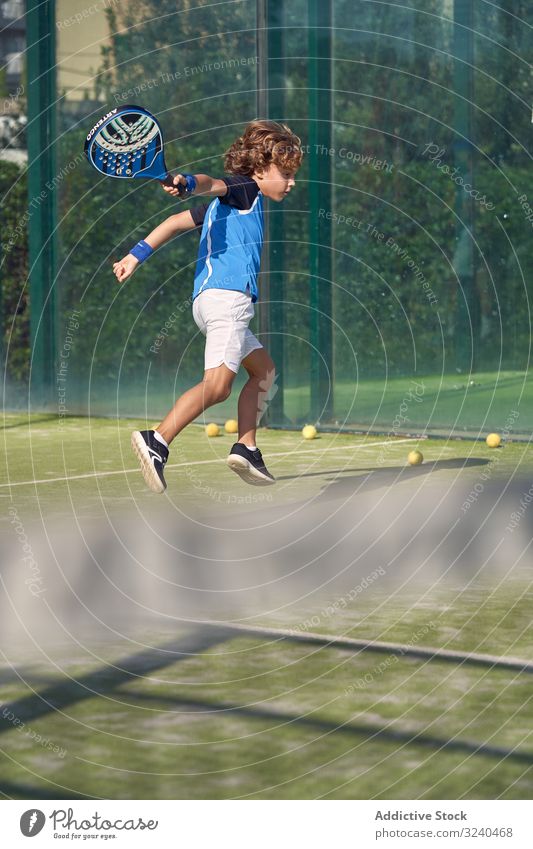 Boy playing tennis on court boy paddle swing match training sport activity kid child racket childhood lifestyle game focused concentrated sportswear hit energy